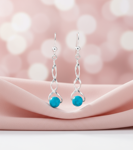 Turquoise earrings on pink fabric