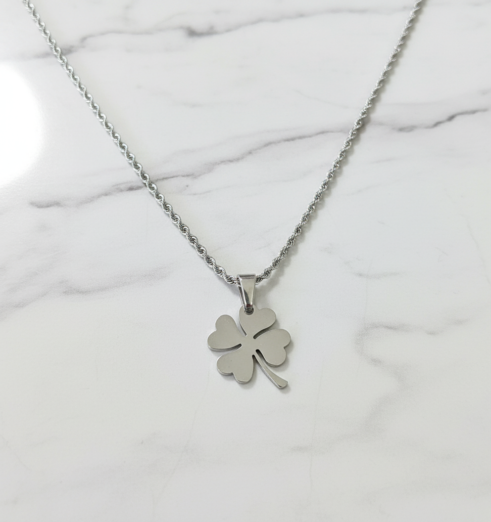 Silver clover necklace on white marble background
