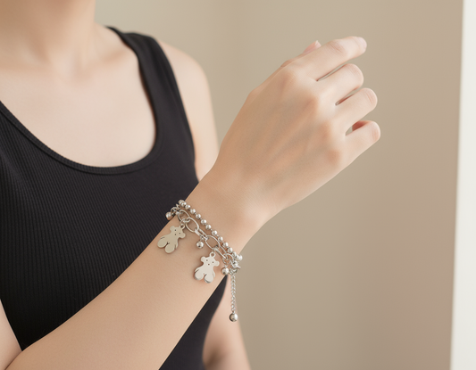Woman's wrist wearing silver layered bracelet with teddy bear charms